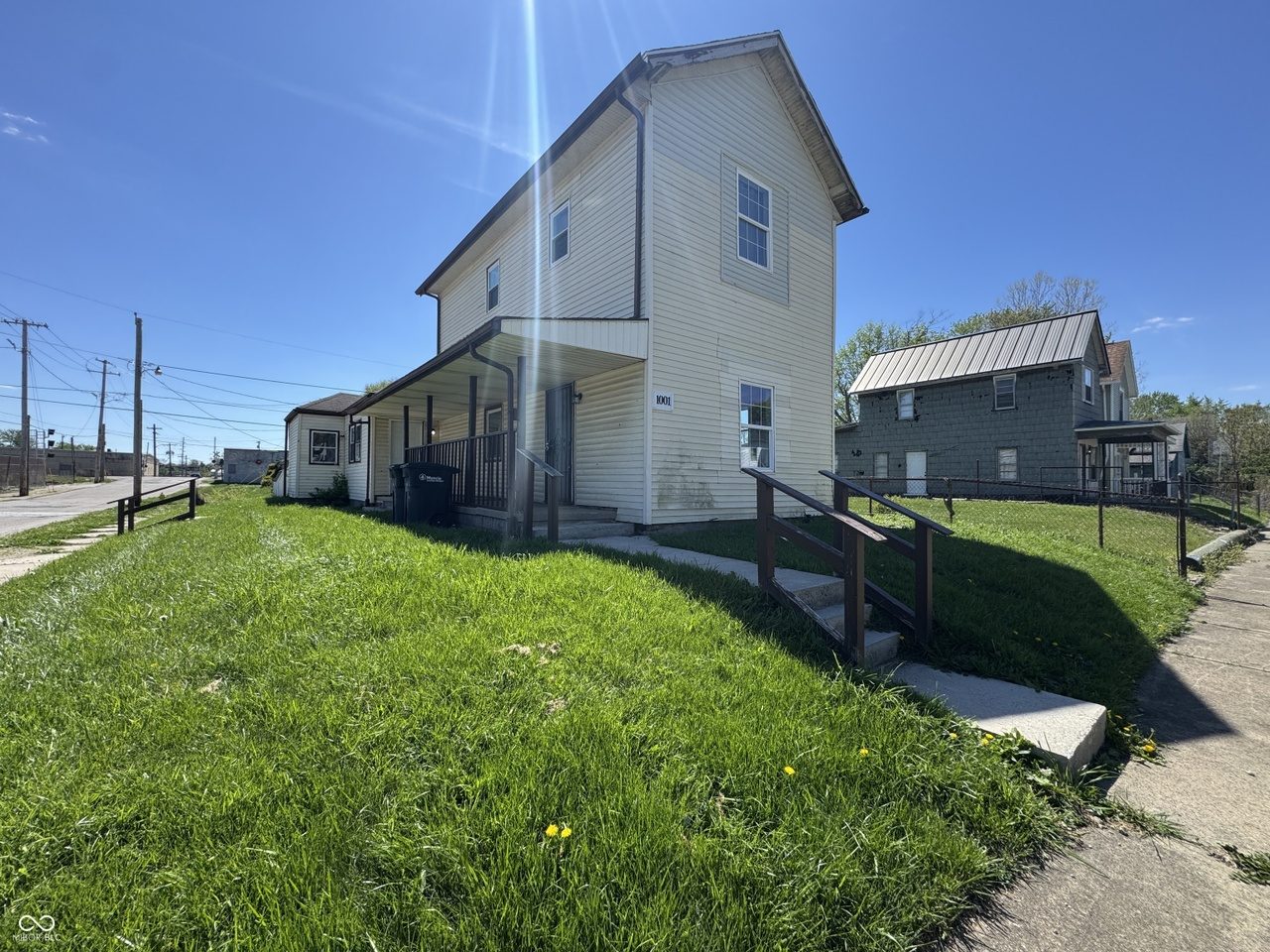 1001 W 1st St — two-story duplex, white siding, covered front porch, corner lot